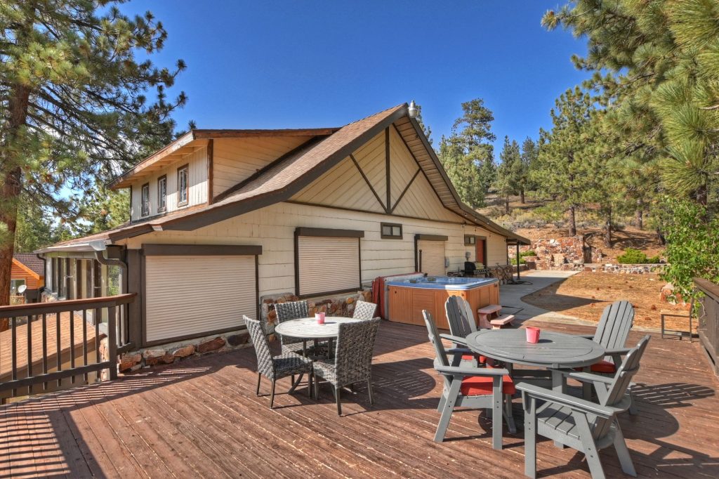 Big Bear mountain cabin deck with outdoor seating, hot tub, and peaceful forest surroundings