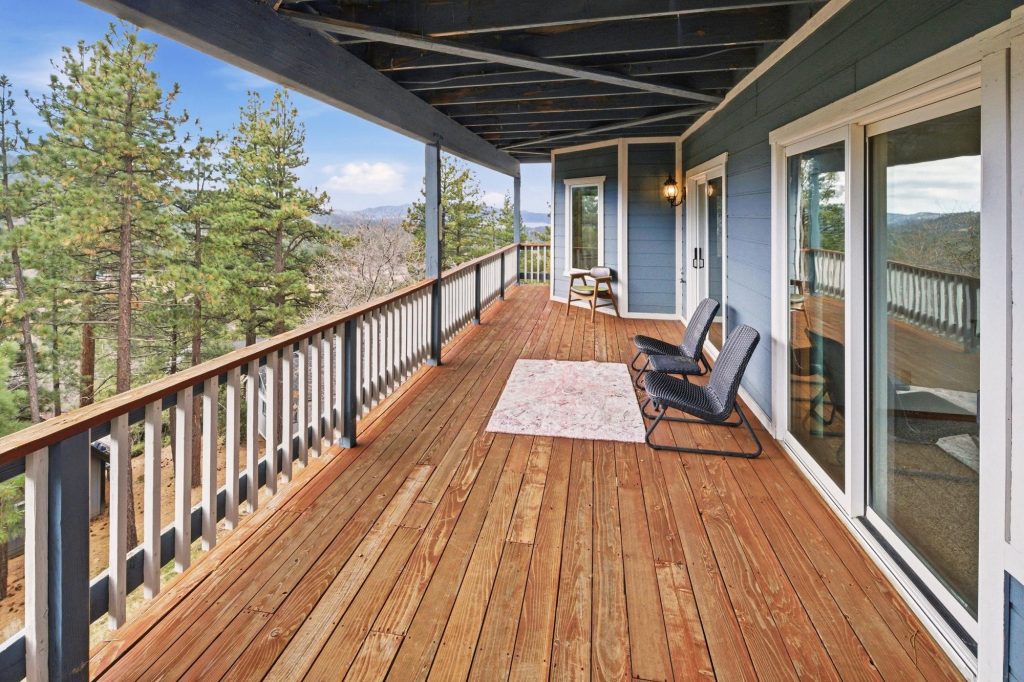 Spacious Big Bear cabin balcony with wooden deck seating and scenic mountain forest views