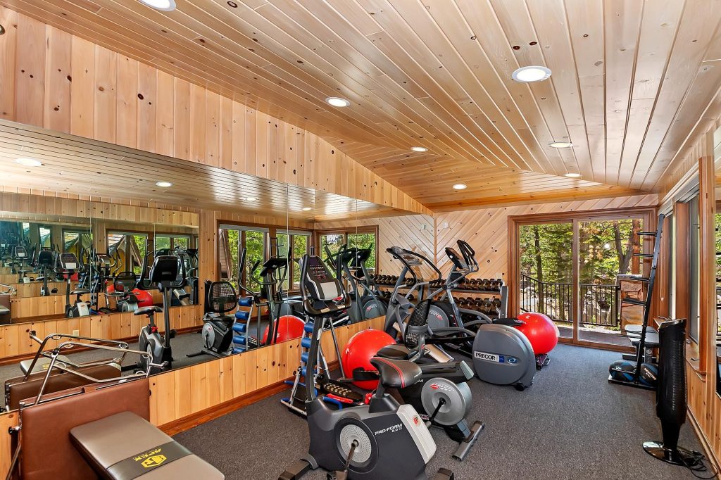 Private fitness room at Edgewood Mansion with cardio machines, weights, and mirrored walls.