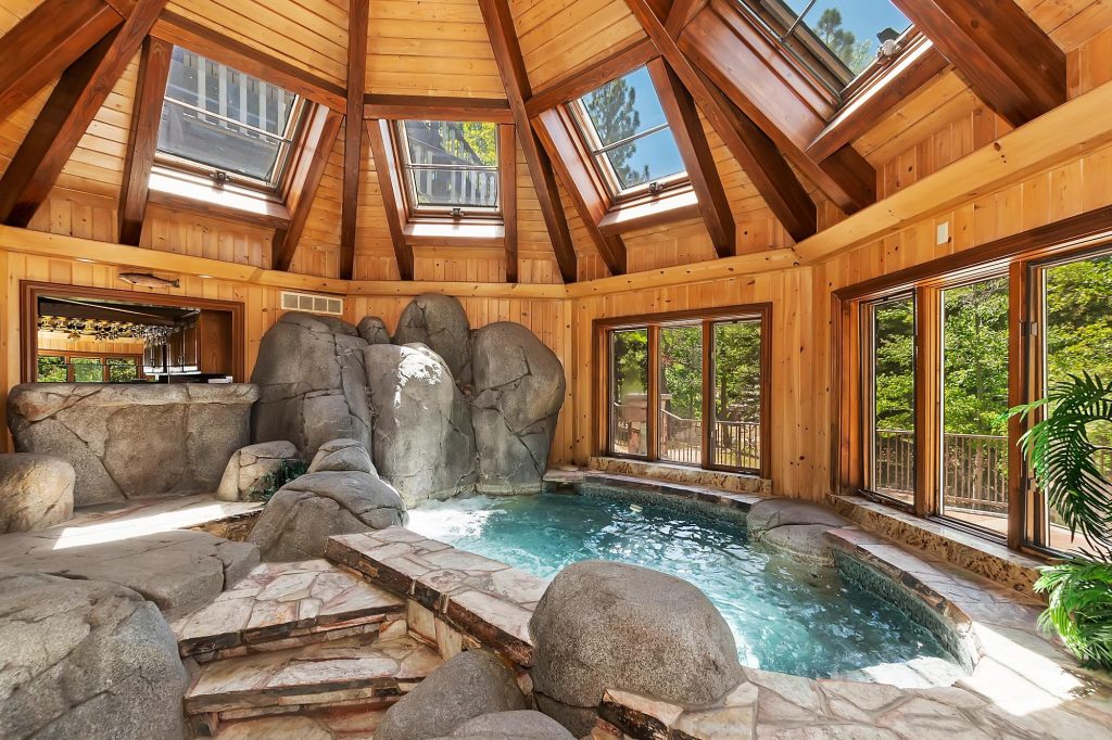 Luxury indoor rock jacuzzi and spa area at Edgewood Mansion with skylights and natural wood architecture.