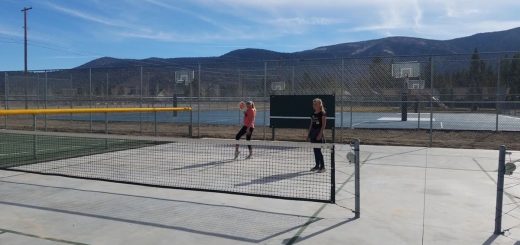 Players playing pickleball on an outdoor court with fencing, mountain scenery, and clear skies at Erwin Lake Tennis Ranch.