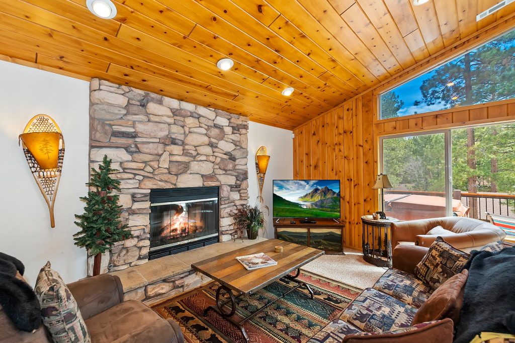Cozy luxury cabin living room with stone fireplace, wooden ceiling, mountain cabin interior, and rustic seating area