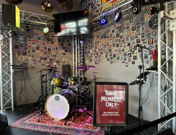 Live music stage setup at Fire Rock Burgers & Brews featuring drums, lighting, and performance equipment
