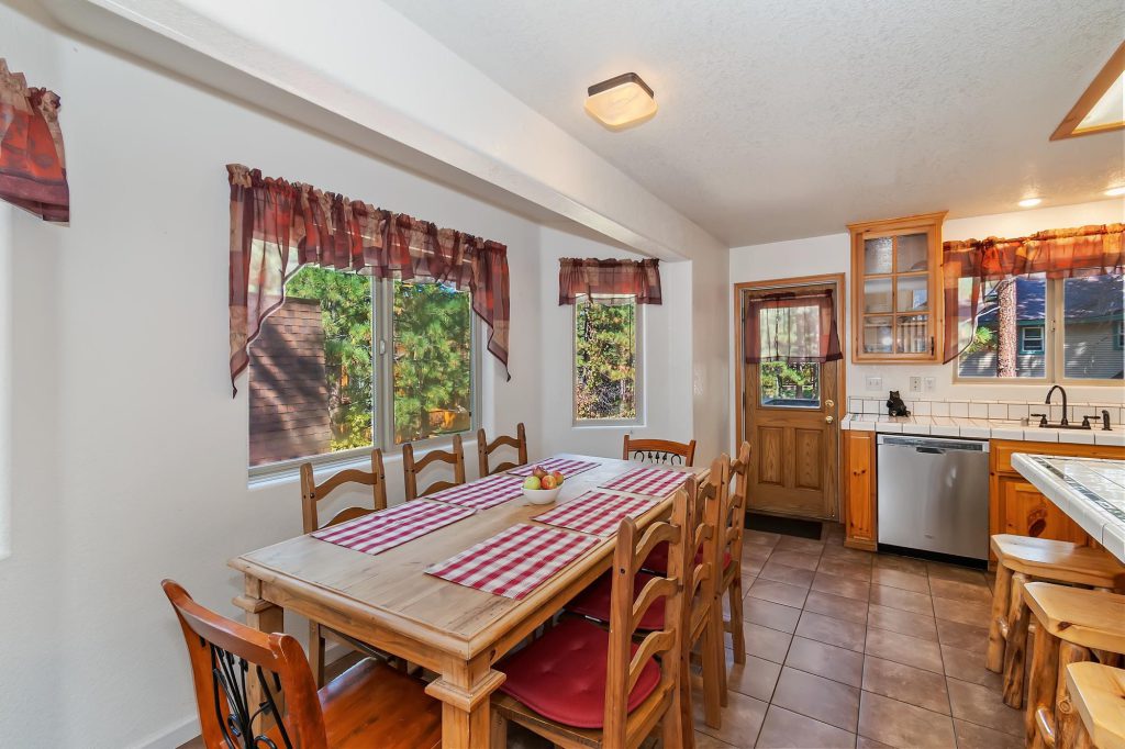 Updated Forest Hollow Big Bear cabin dining area with wood dining table and kitchen