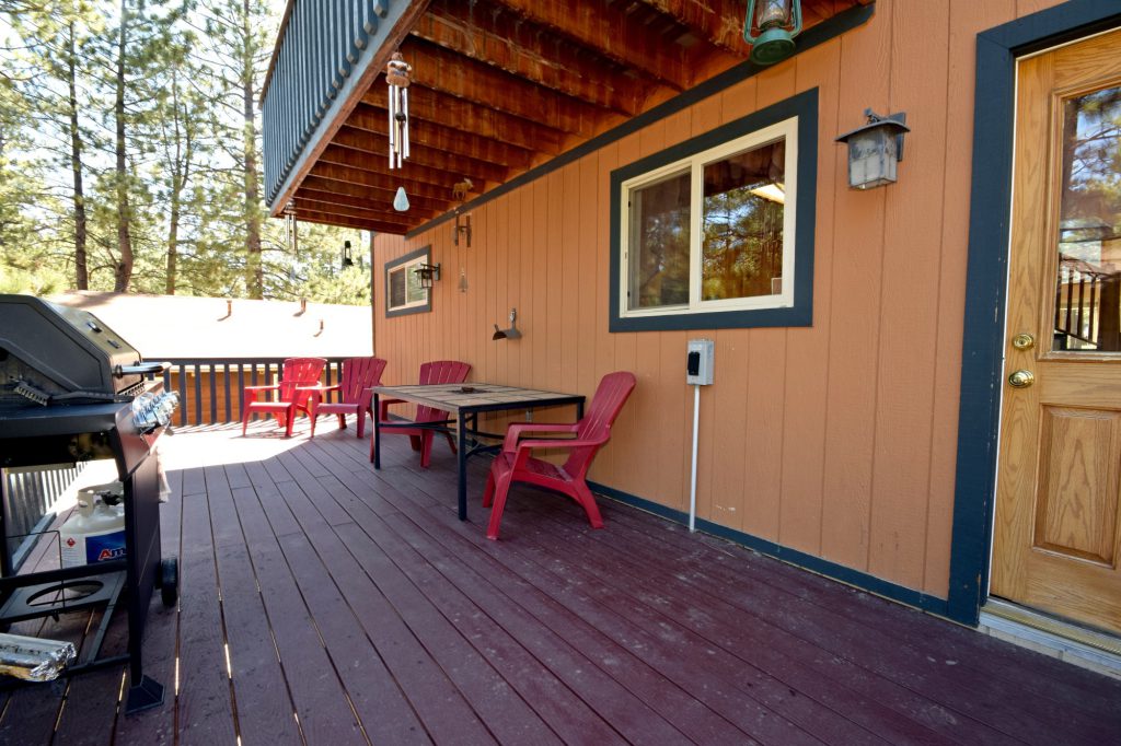 Original patio seating at Forest Hollow Big Bear deck with red chairs and grill