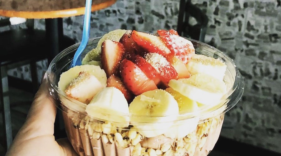 A person holding a bowl filled with fruit and cereal at Frusion Juice and Coffee in Big Bear.