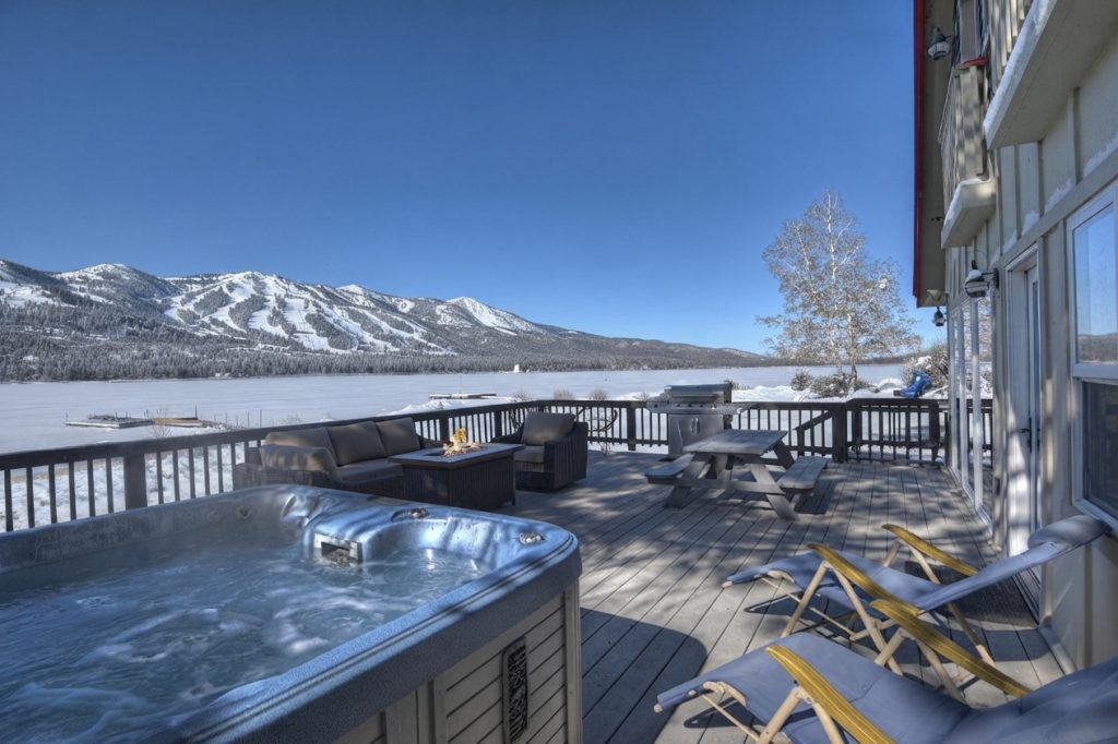 Snow-covered Big Bear lakefront deck with hot tub and mountain views during winter