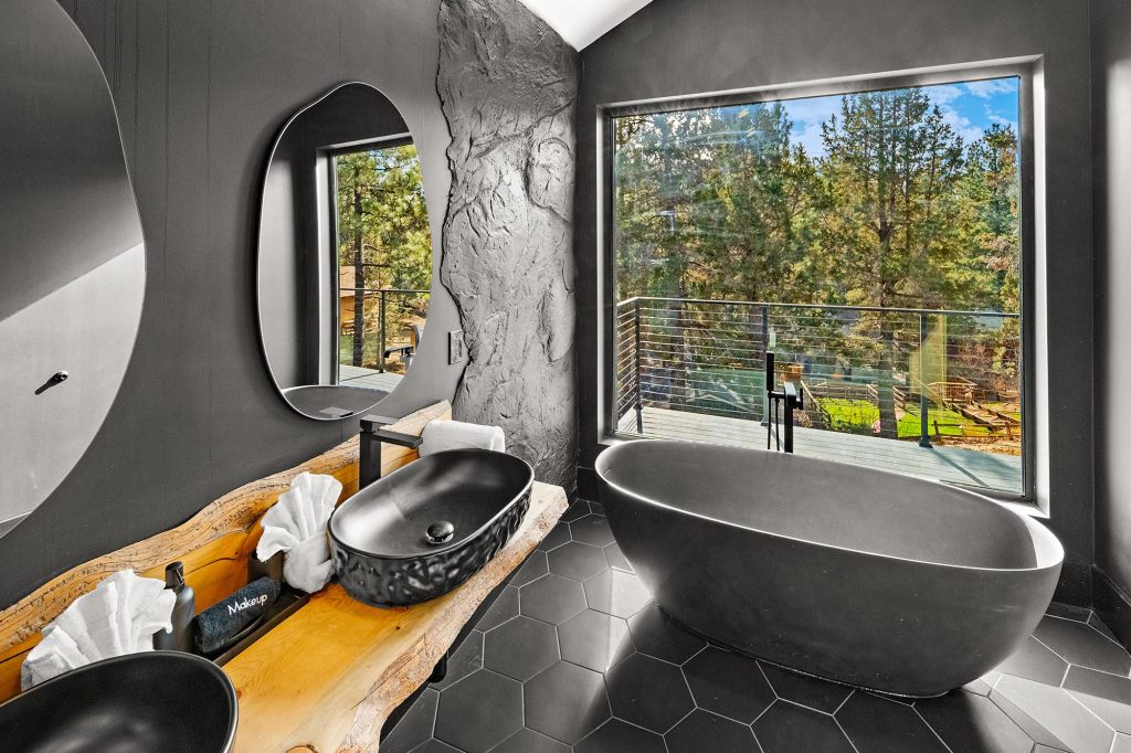 Elegant spa-style bathroom at The Getaway Club with freestanding soaking tub and forest views.