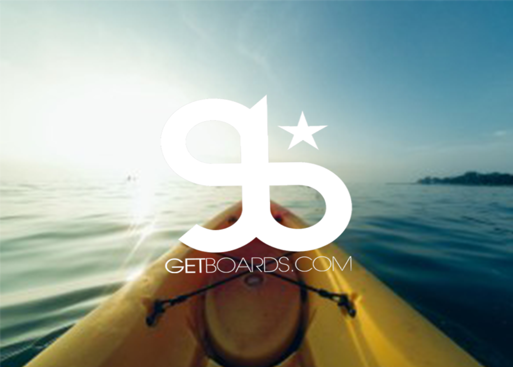 A view from a kayak on a calm lake in Big Bear, with a sunlit sky and the logo for "Getboards.com" overlaid on the image.