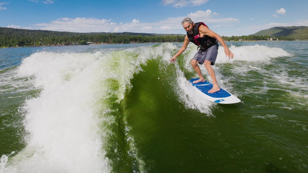 Person wakesurfing across the waves on Big Bear Lake during an outdoor water adventure.