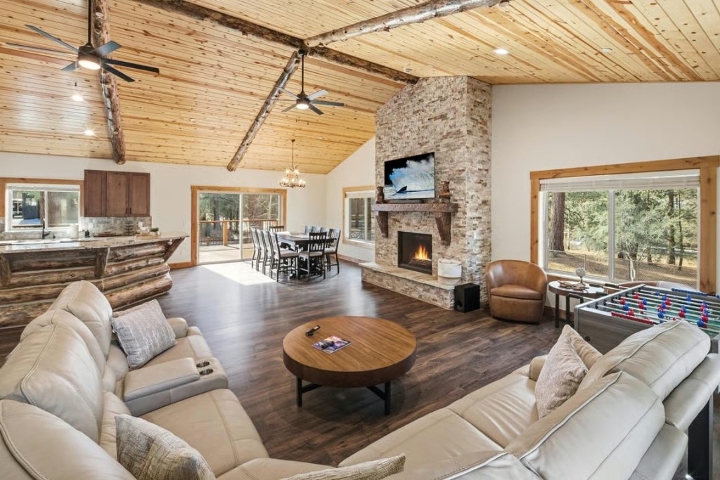 Spacious Big Bear cabin living area with a stone fireplace, comfortable sofas, dining space, and foosball table
