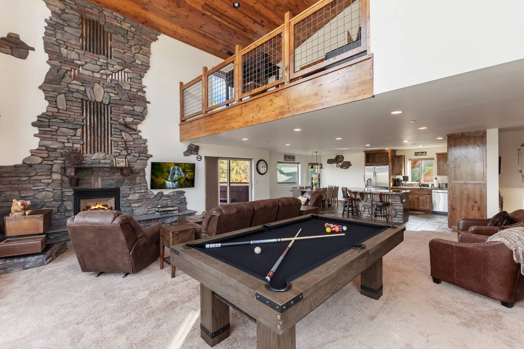 Spacious great room at Goldmine Lakeview featuring a stone fireplace, pool table, leather seating, and open mountain cabin design