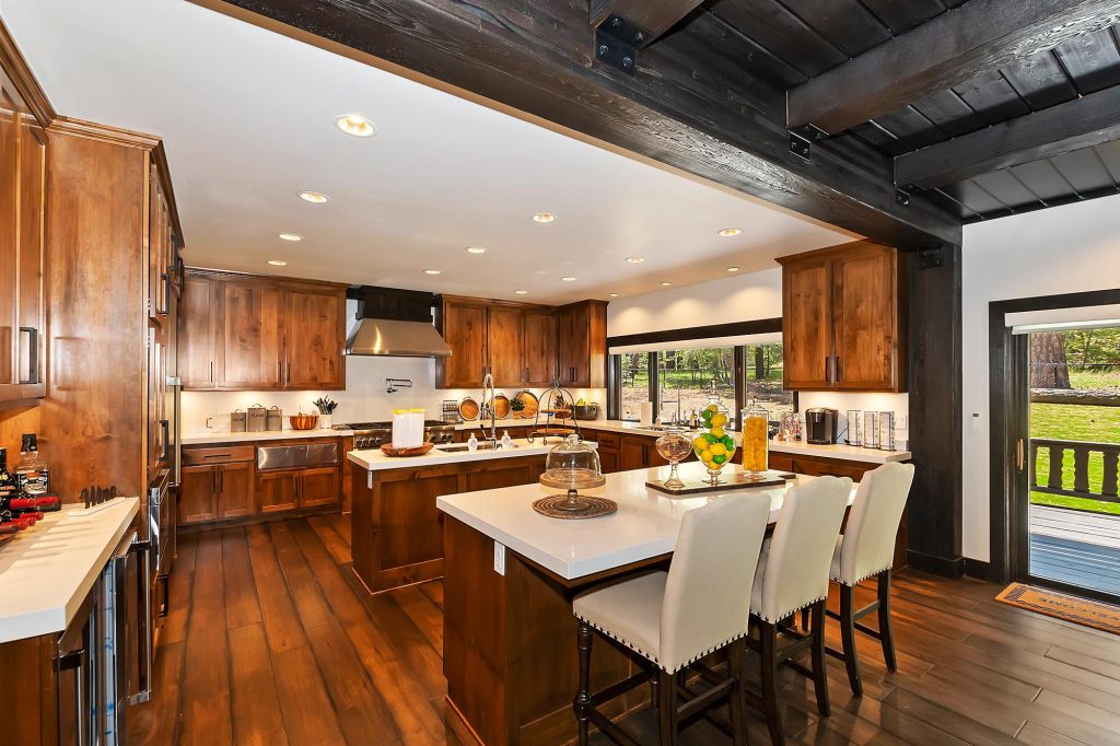 Spacious modern kitchen featuring wooden cabinets, large island countertop, bar seating, and premium appliances