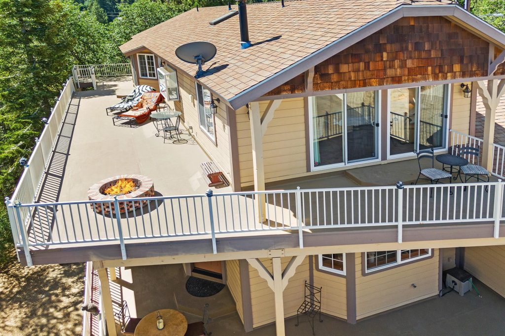 Spacious outdoor deck with fire pit, lounge seating, and mountain cabin exterior