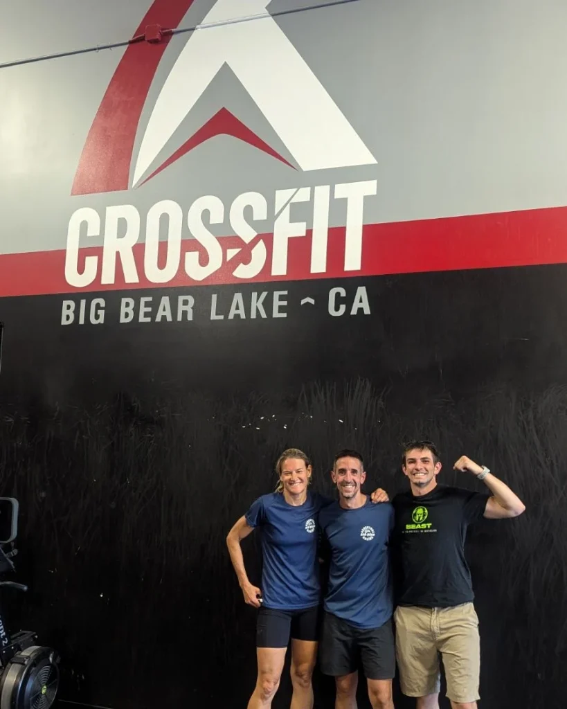 Three people posing together inside a CrossFit gym in Big Bear Lake, standing in front of a wall with “CROSSFIT BIG BEAR LAKE CA” signage.