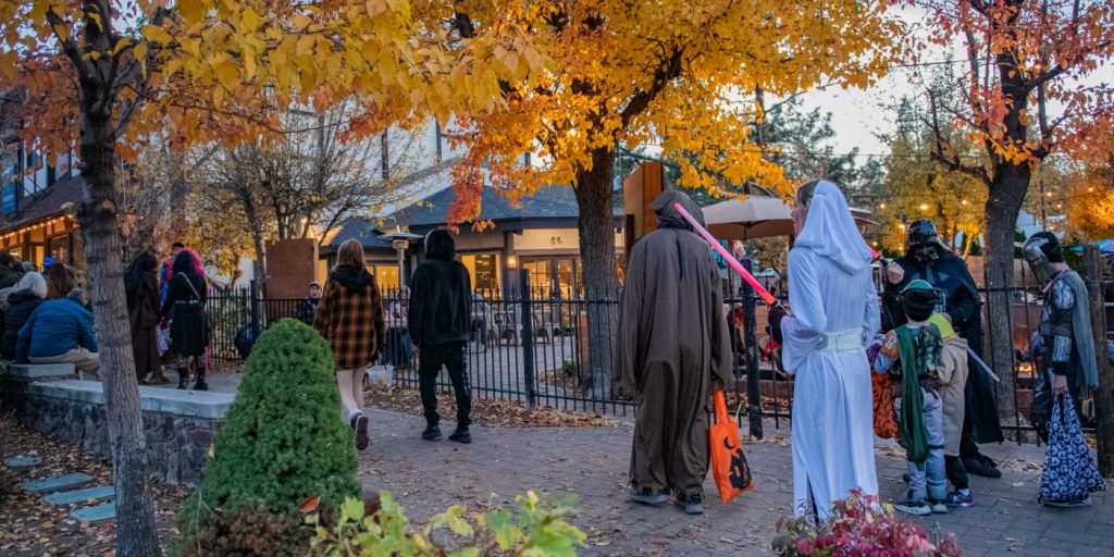 Families and visitors in Halloween costumes enjoying a festive evening in The Village at Big Bear Lake
