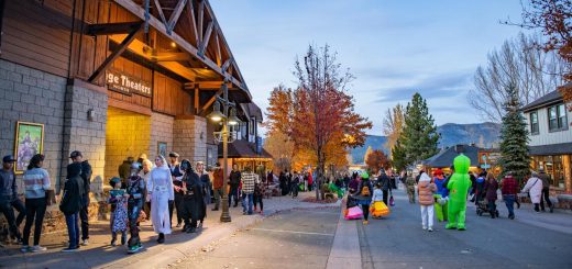 Halloween in the Village in Big Bear with people in costumes walking down the street with fall trees behind