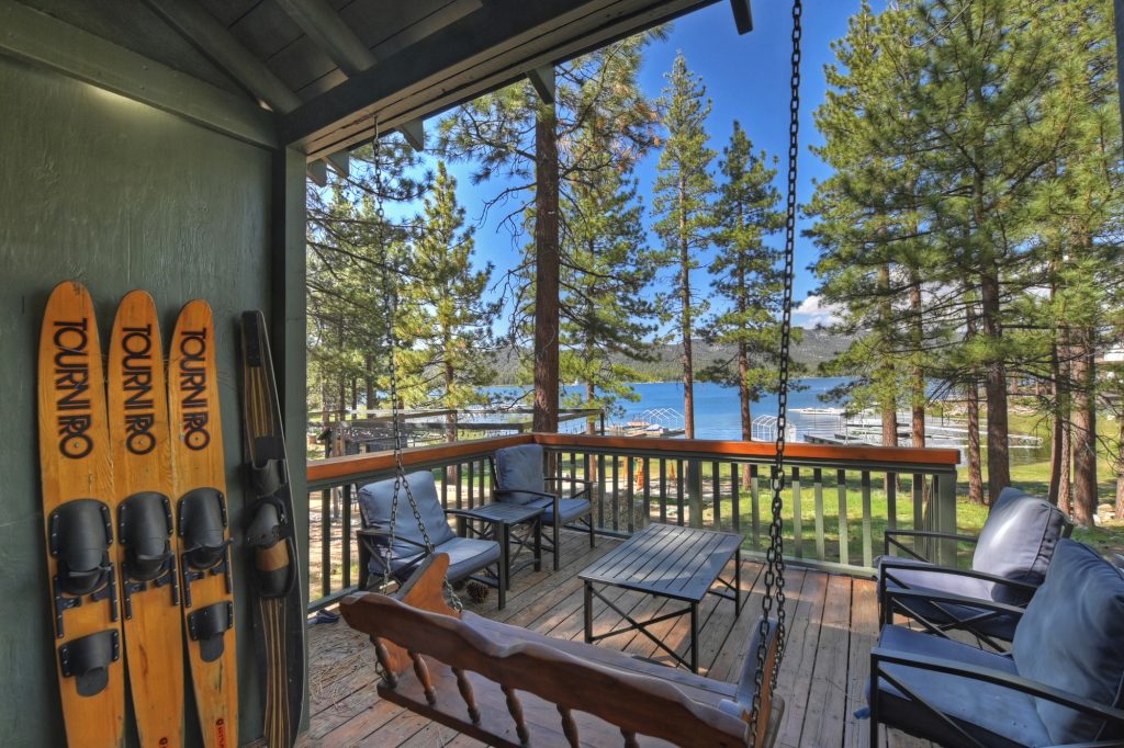 Back patio of Happy Little Cottage featuring outdoor seating, swing, ski decor, and scenic lake and mountain views