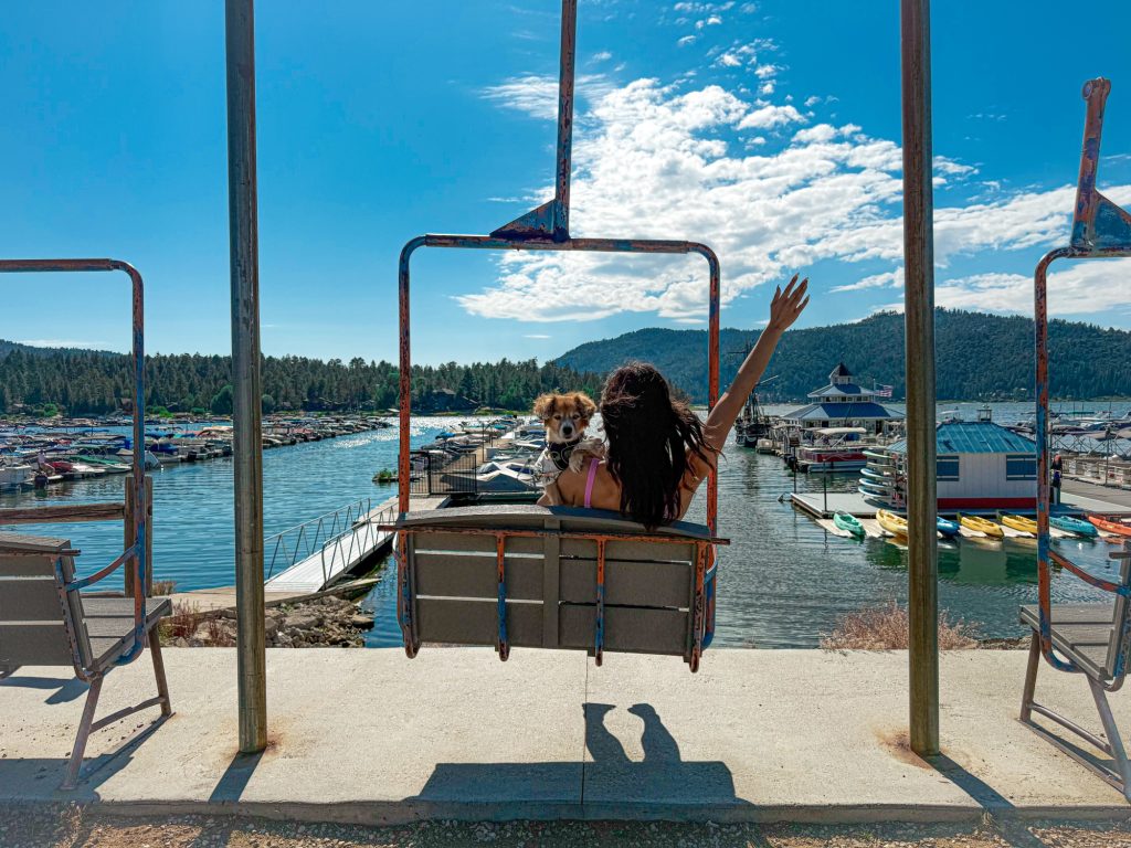 Scenic Big Bear Lake view with marina, mountains, blue sky, and chairlift ride