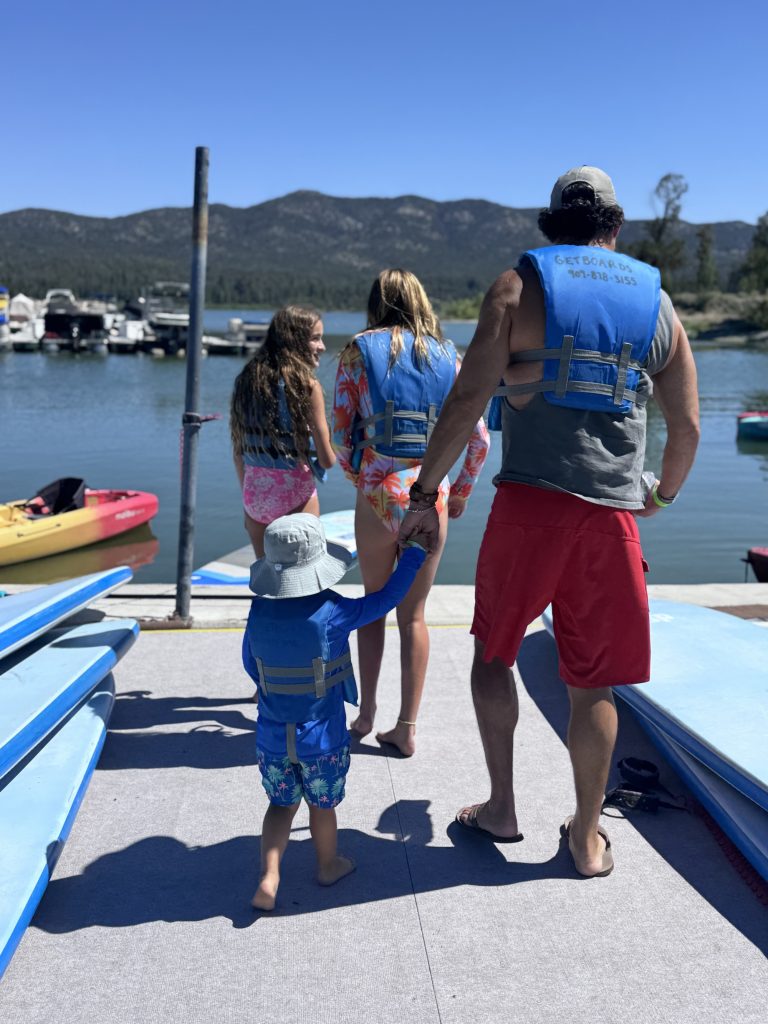 Family wearing life jackets walking toward paddleboards and the lake at Big Bear.