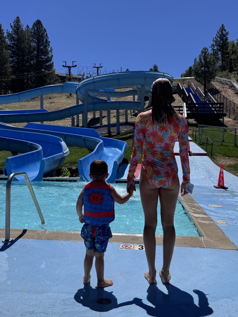 Adult and child standing beside the water slides at Big Bear's alpine water park.