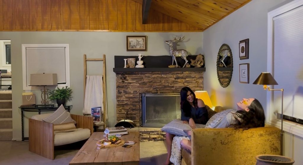 Cozy cabin living room with stone fireplace, comfortable seating, and warm rustic interior