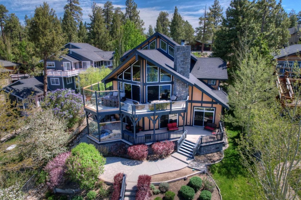 Aerial view of a mountain home with multiple decks surrounded by trees in Big Bear