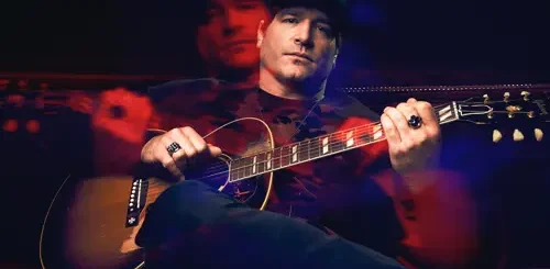 Jerrod Niemann sitting on a couch with an acoustic guitar during a concert at Big Bear Lake.