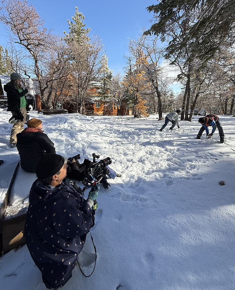 A group of people sitting together in the snow during a Kim Lansell Production in Big Bear.