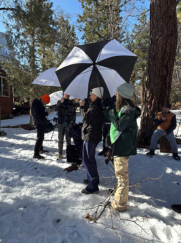 A group of people standing together in the snow during a Kim Lansell production scene in Big Bear.