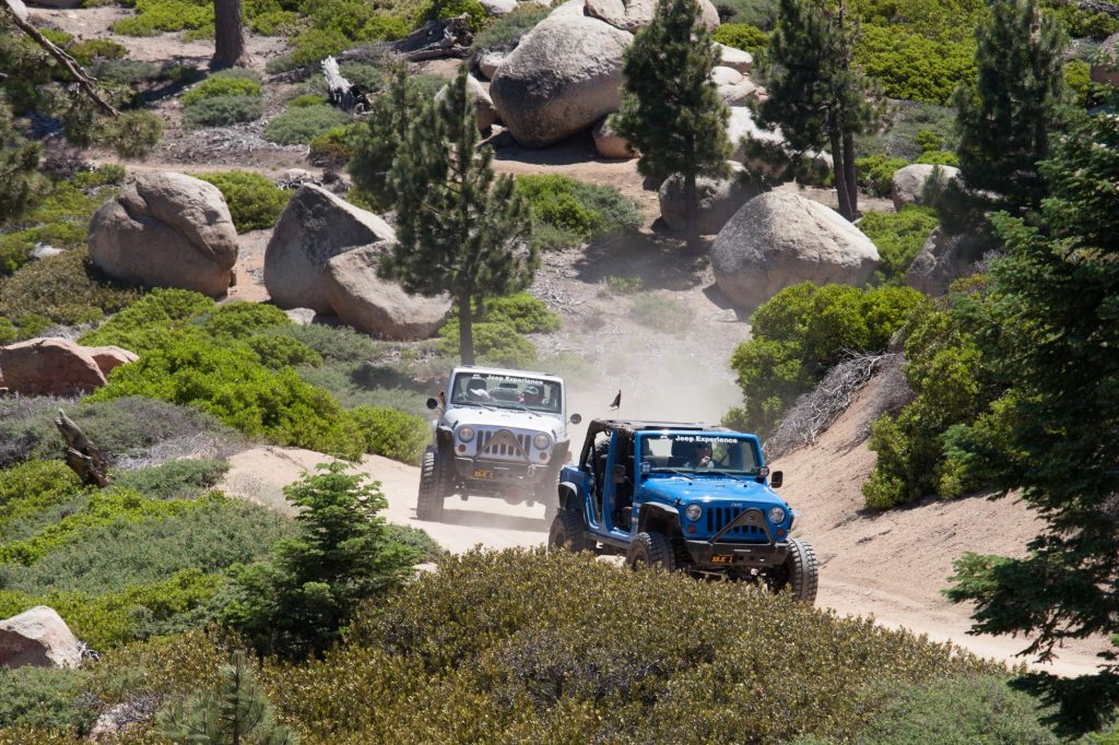 Two Jeeps driving on a rugged off-road trail through the scenic forest and granite boulders in Big Bear Lake.
