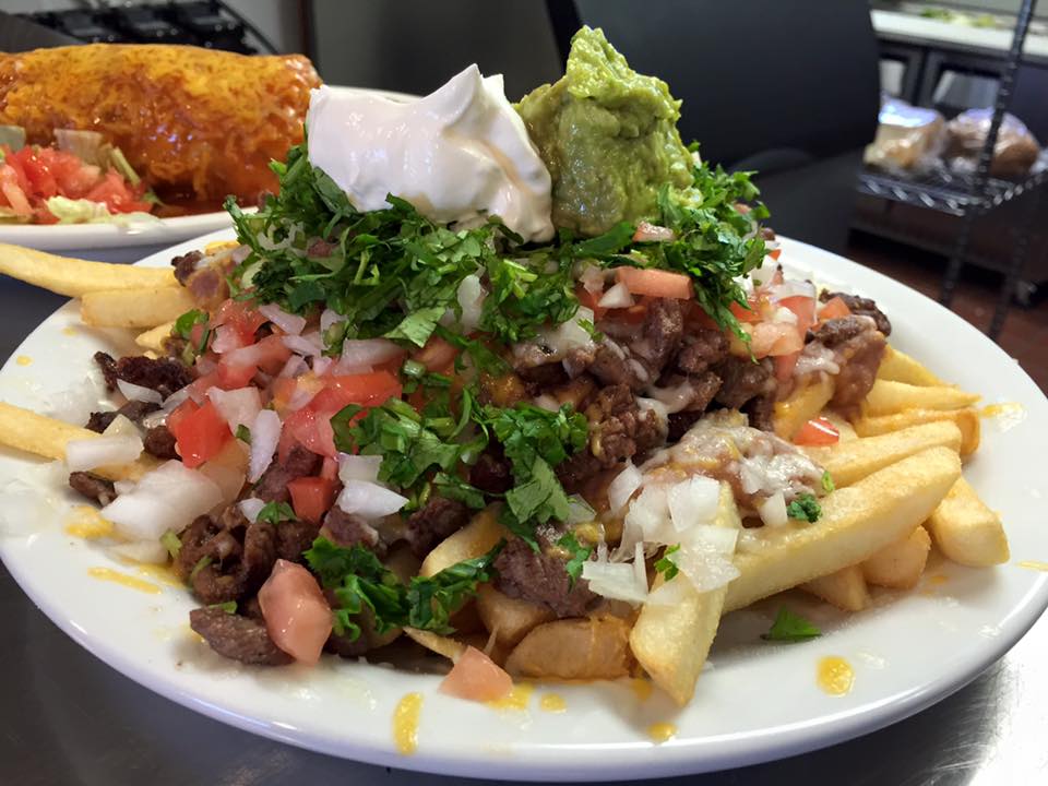 A close-up shot of a plate of carne asada fries topped with guacamole, sour cream, pico de gallo, and cilantro from a restaurant in Big Bear.