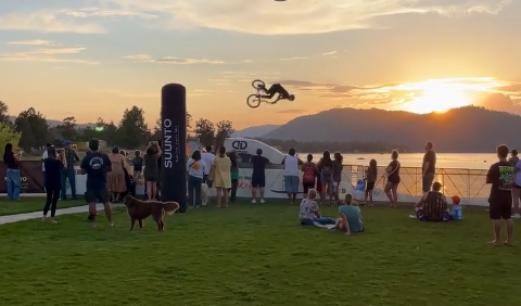 BMX athlete performing a high-flying stunt during the Lakefest BMX show with spectators watching by the lake at sunset