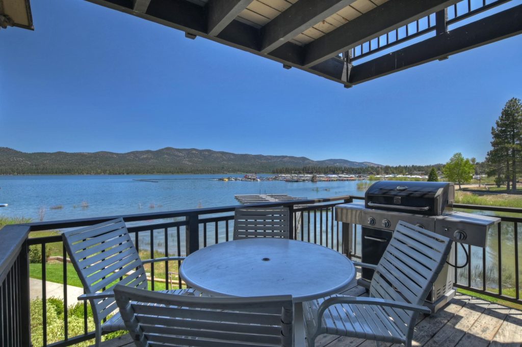 Lakefront cabin balcony with outdoor seating, grill, and scenic mountain lake views