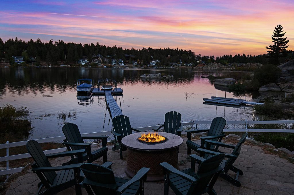 Firepit seating overlooking Big Bear Lake at sunset with dock and lakefront homes