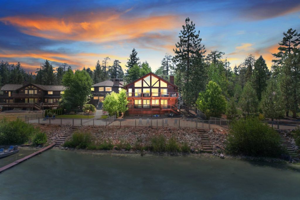 Lakefront cabin with illuminated windows and lake access during sunset