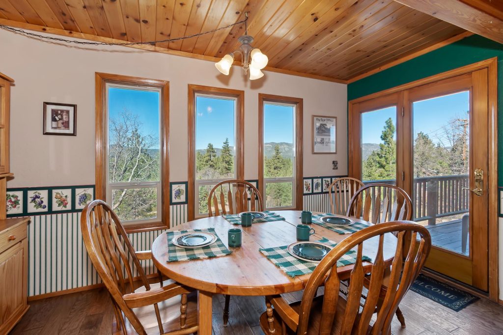 Cozy cabin dining room with wooden table, mountain view windows, and rustic interior seating area