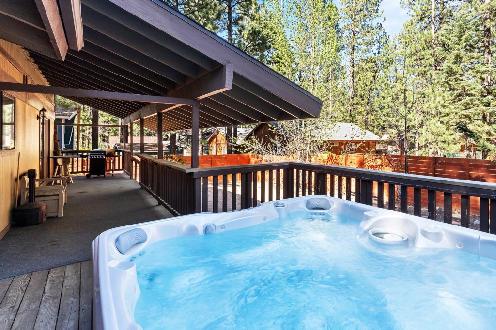 Covered Big Bear cabin patio with private hot tub, BBQ grill, and relaxing forest views