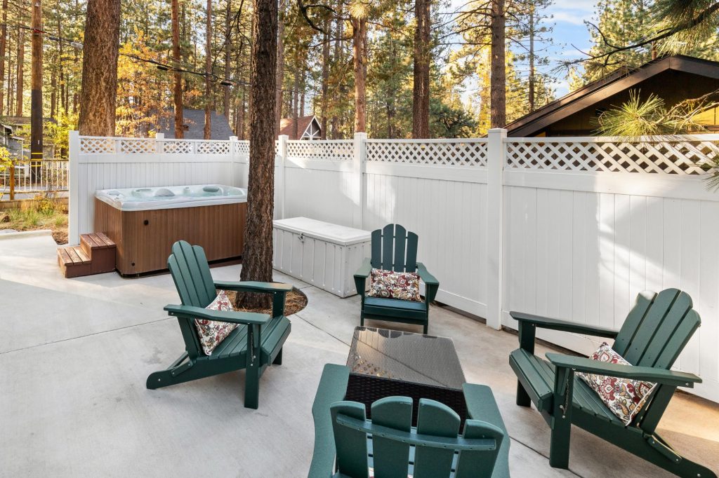 Private outdoor patio with Adirondack chairs and hot tub surrounded by pine trees