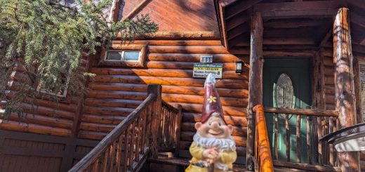 Entrance of Bear Butte Lodge with a cheerful garden gnome and rustic log cabin charm.