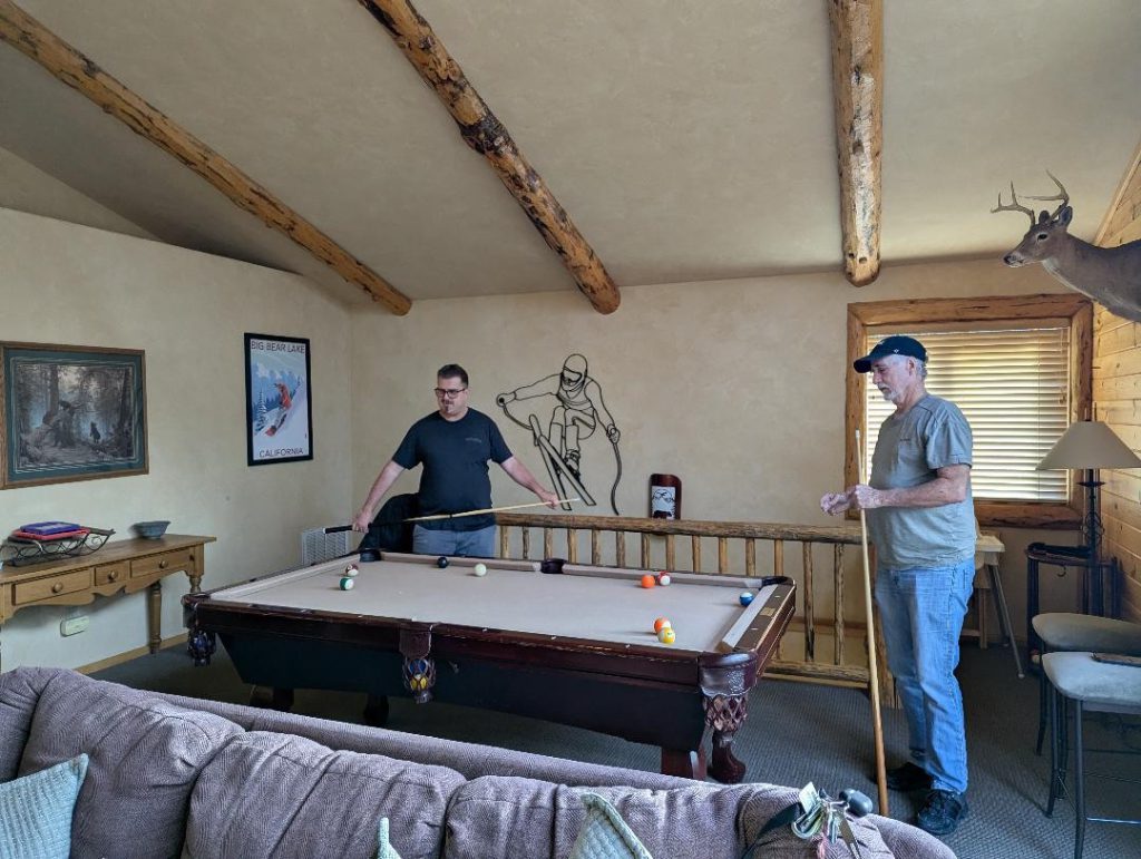 Guests enjoying a game of pool in a cozy Big Bear cabin with rustic decor.