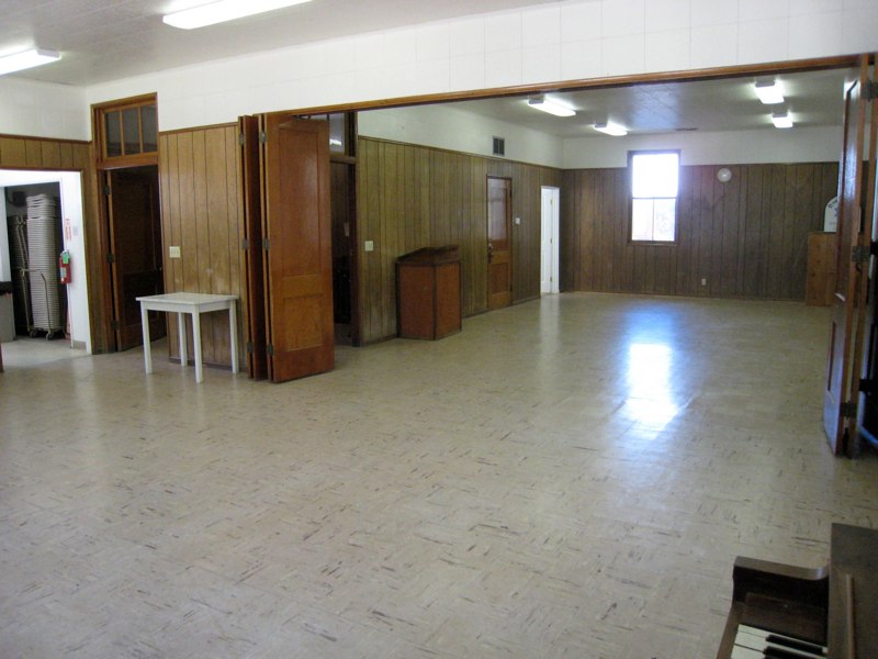 Interior community meeting room at Miller Park in Fawnskin featuring an open gathering space, wood-paneled walls, and historic schoolhouse charm near Big Bear Lake.