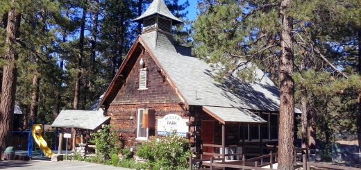 Historic Miller Park building in Big Bear surrounded by tall pine trees, with nearby playground and community recreation facilities.