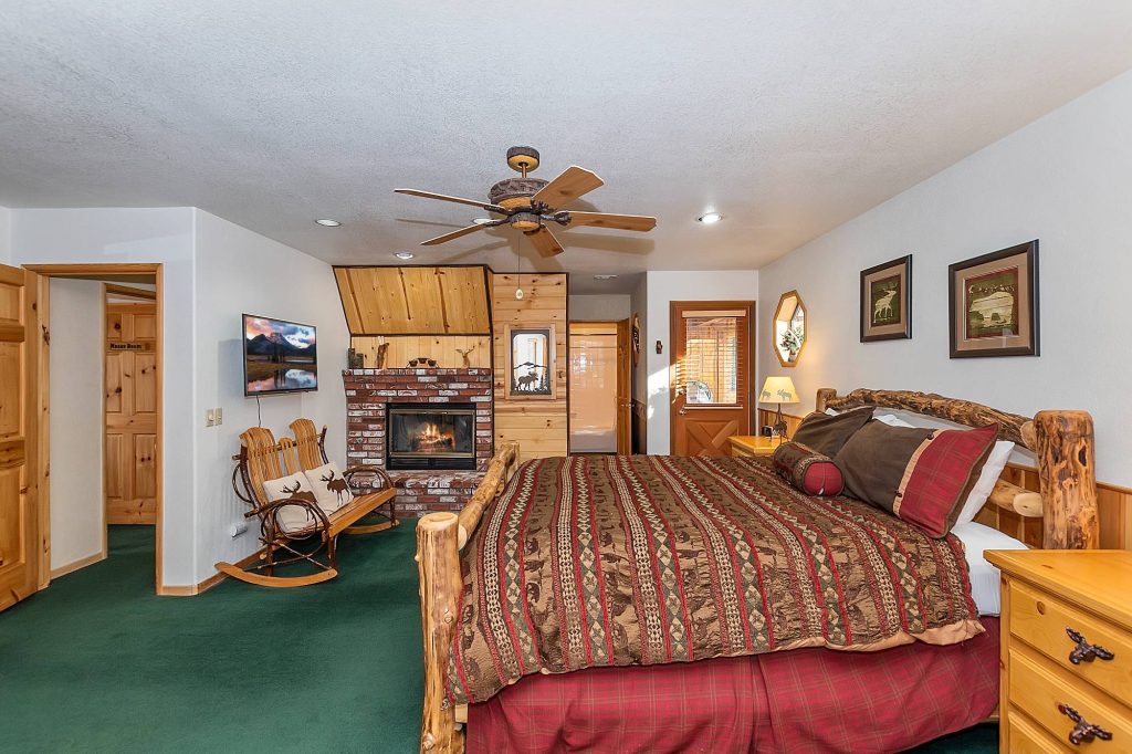 Rustic master bedroom with log bed, brick fireplace, and mountain-inspired décor