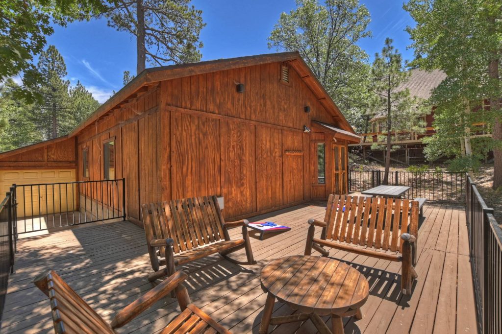 Outdoor deck with rustic seating and gathering space surrounded by pine trees