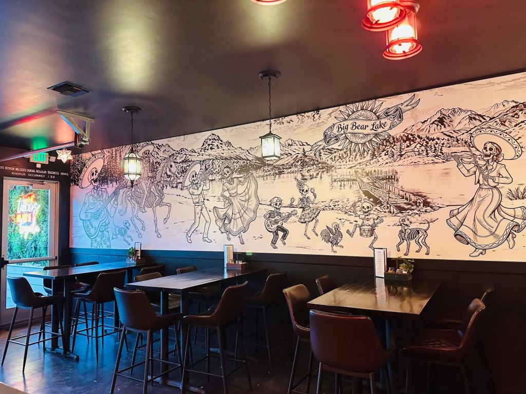 Hand-drawn mural and indoor seating showcasing the vibrant atmosphere of Muchachos Urban Cantina.