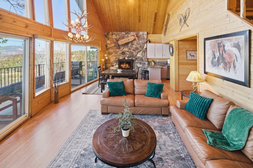 Nature's Dream cabin living room with leather sofas, stone fireplace, and open mountain view windows