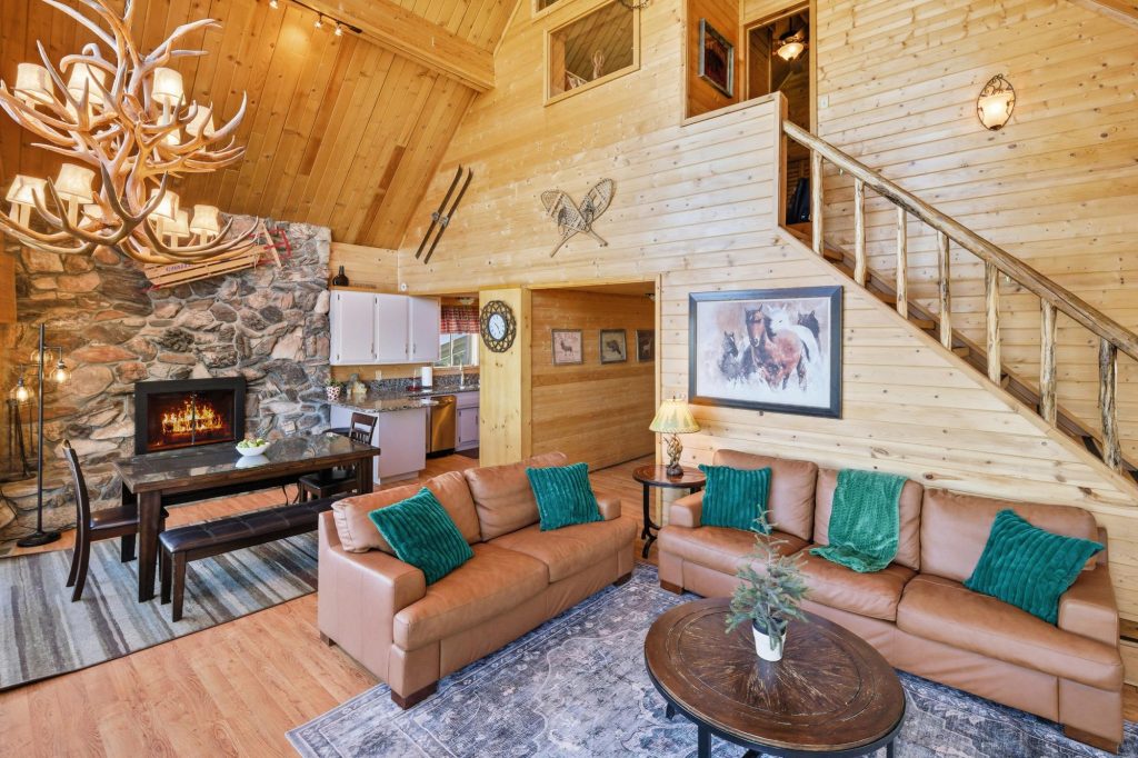 Nature's Dream open concept living room with loft stairs, leather sofas, and fireplace