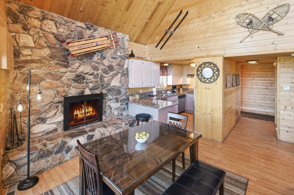 Nature's Dream dining area with stone fireplace and open kitchen