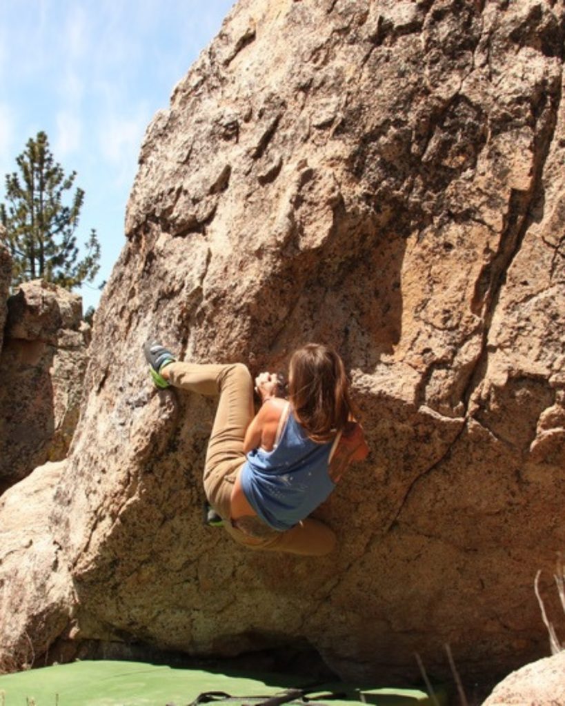 A climber practices bouldering on a large granite rock at North Shore Boulders in Big Bear.